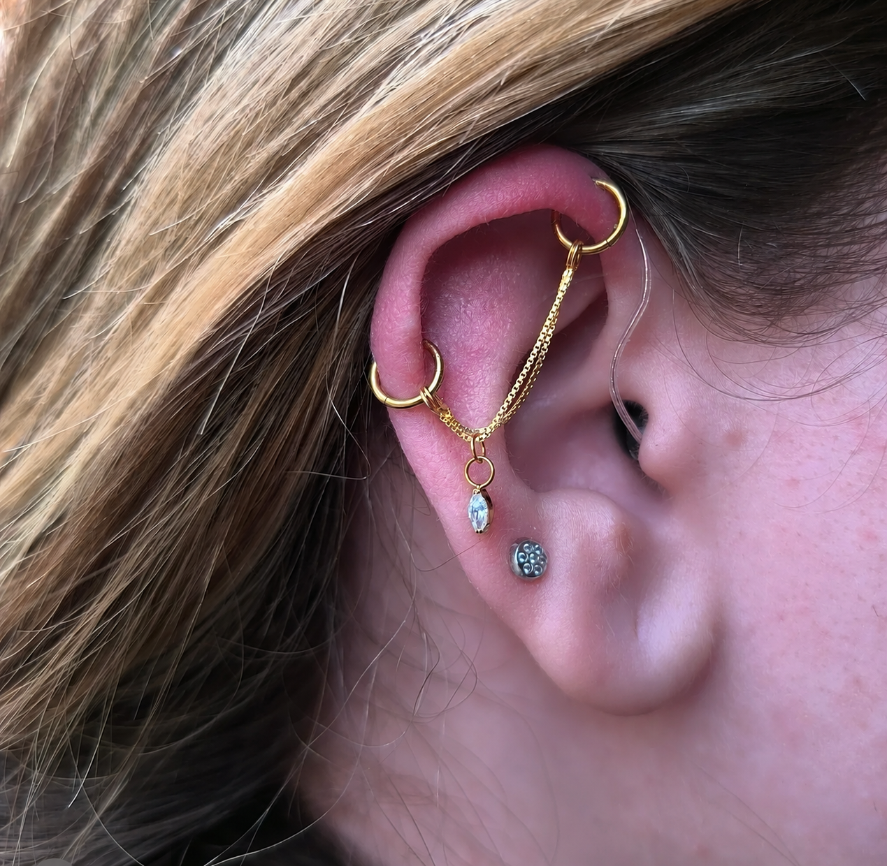 Ohrpiercings mit goldfarbenen Ringen und Ketten