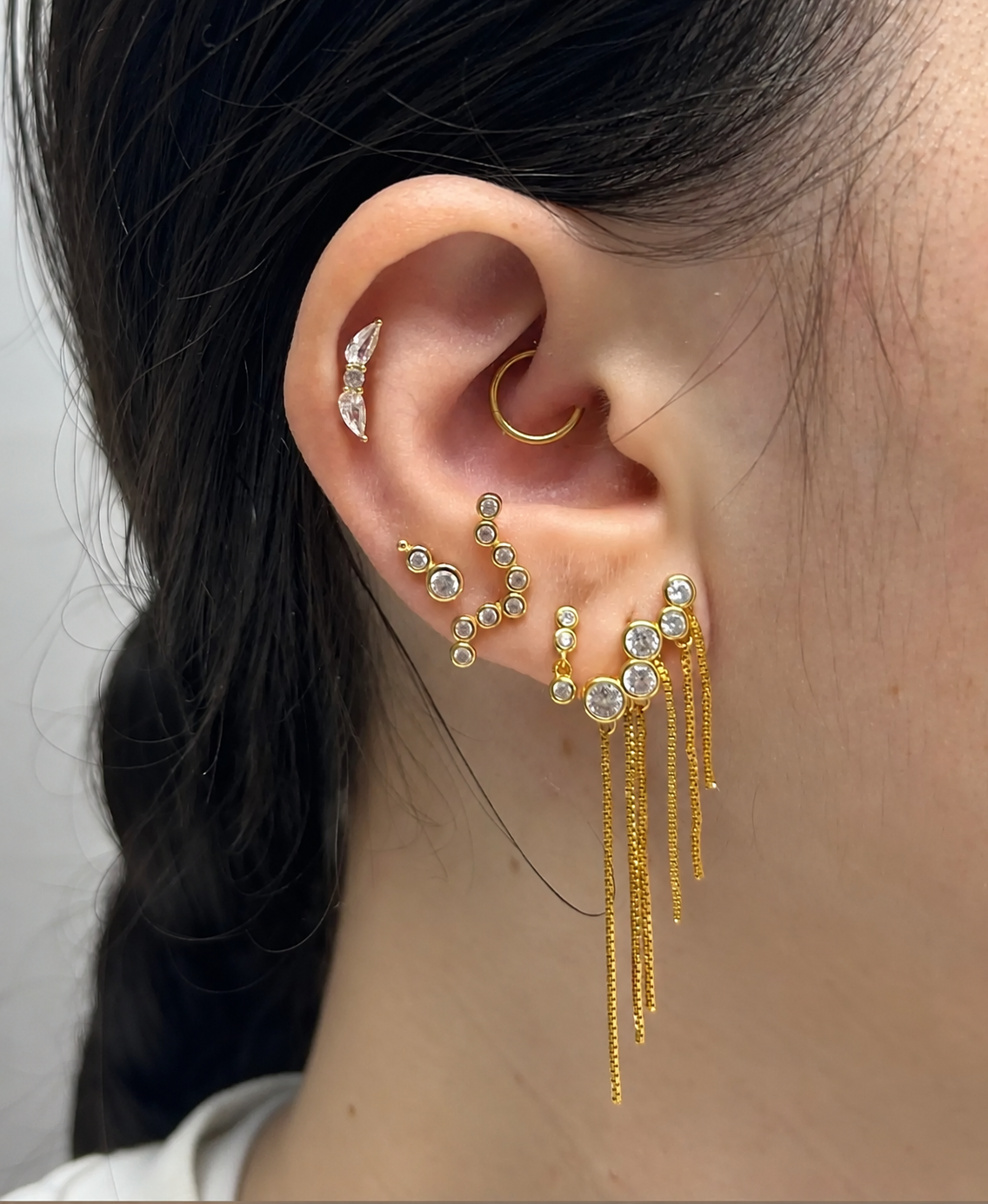 Ohrpiercing-Komposition mit goldfarbenem Schmuck